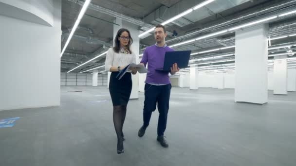 Una mujer y un hombre especialistas en arquitectura están caminando por el edificio — Vídeo de stock