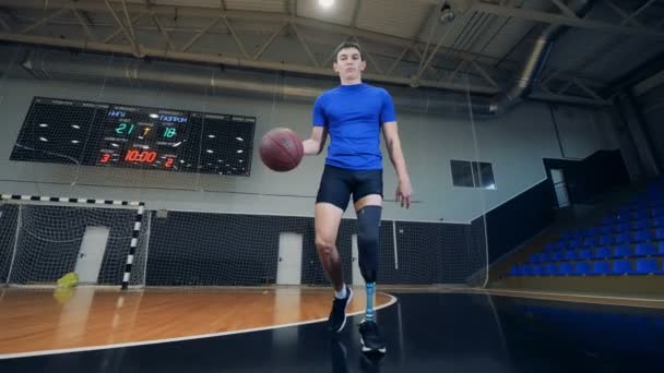 Nizhny Novgorod, Rusia - CIRCA Noviembre 2018: Gimnasio vacío y un hombre con una pierna protésica haciendo una práctica de baloncesto — Vídeos de Stock