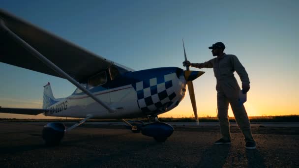 Mannelijke piloot veegt een propeller vliegtuigen, zijaanzicht. — Stockvideo