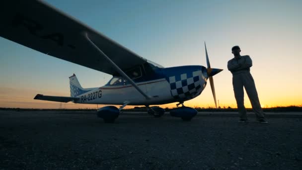 Person stands on a runway near a small plane, close up. — Stock Video