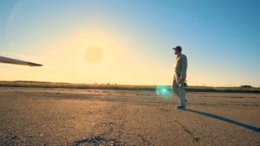 Erkek havacı bir uçak için yürür ve denetler, yan görünüm.