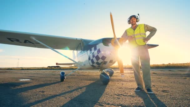 Aviator áll közel egy repülőgép a susnet háttér, közelről. — Stock videók