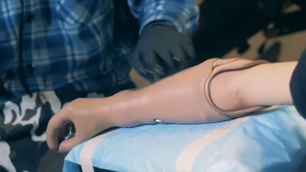 A mão protética está a ser tatuada por um mestre masculino. — Vídeo de Stock