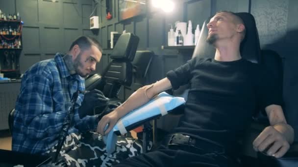 Tattoo salon met een gehandicapte man, het verkrijgen van een tatoeage op zijn prothese — Stockvideo