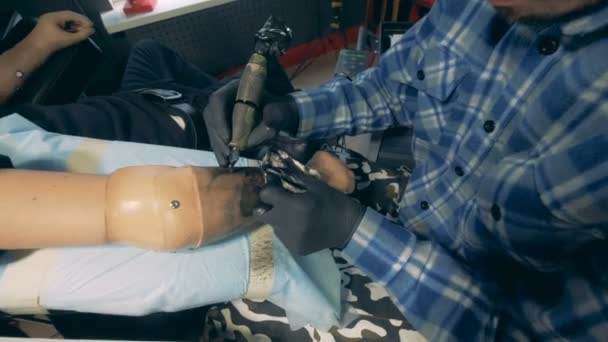 Um homem com mãos protéticas está recebendo uma aplicação de tatuagem — Vídeo de Stock