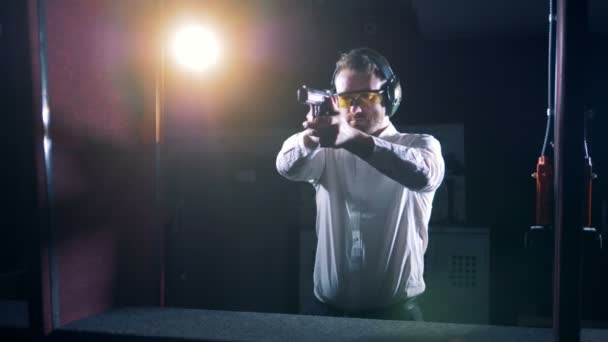 Мужчина стоит на стрельбище с пистолетом, крупным планом . — стоковое видео