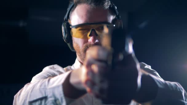 Man i glasögon håller en pistol på ett skytte rum, närbild. — Stockvideo