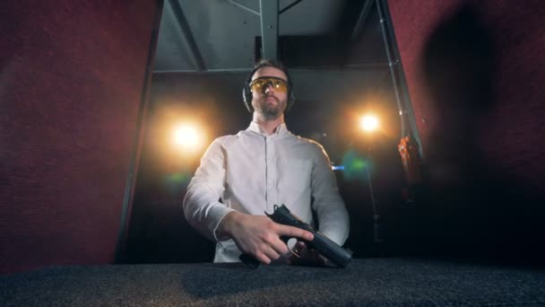 Persoon neemt een pistool in een schietpartij kamer, onderste weergave. — Stockvideo