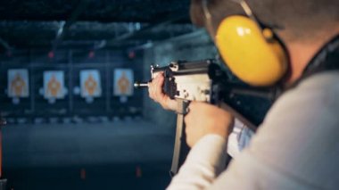 Bir hedef çekim mesafeden bir tüfekle hedefleyen bir adam arkadan görünüm.