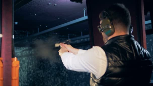 De praktijken van een persoon op een schietbaan, afvuren van een pistool, close-up. — Stockvideo