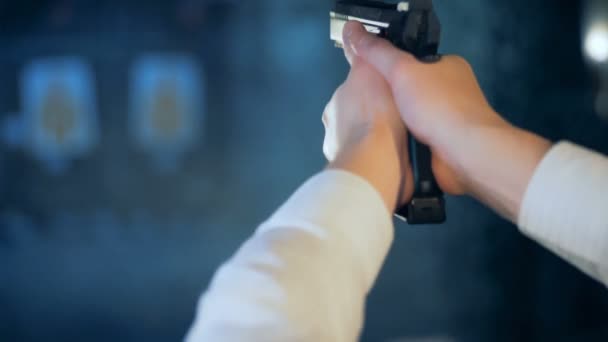Manliga skytten skjuter en pistol i en träningslokal, bakifrån. — Stockvideo