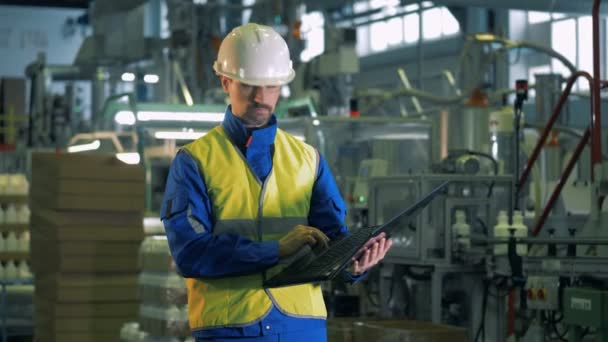 Man controleert fabriek apparatuur met een laptop, geautomatiseerde productie. — Stockvideo