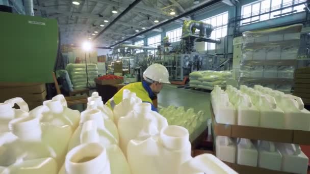 Trabalhador da fábrica coloca caixas com garrafas em uma instalação, processo de envolvimento . — Vídeo de Stock