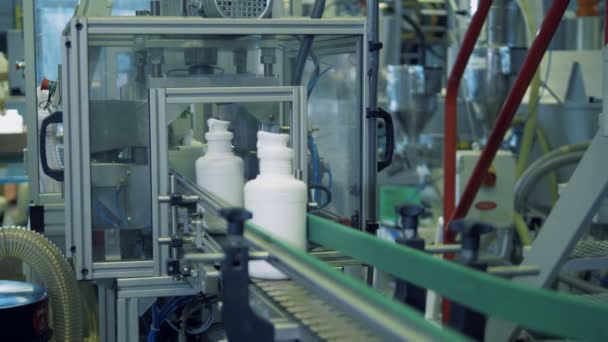 Vita flaskor med kemikalier på en fabrik transportband, automatisk teknik. — Stockvideo