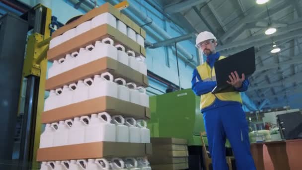 En inslagning utrustning fungerar samtidigt som en man kontrollera det på en fabrik. — Stockvideo