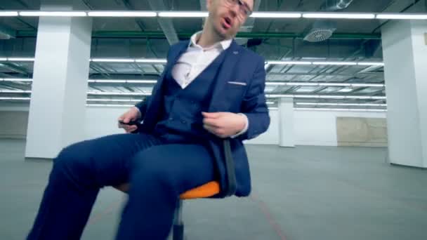 Travailleur de bureau joyeux filant sur une chaise, activité amusante . — Video