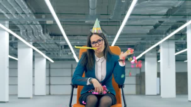 Keder kvindelige arbejdstager kaster konfetti, mens du sidder i en kontorstol . – Stock-video