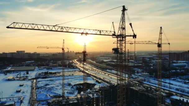 Grúas altas en movimiento mientras se trabaja en una obra de construcción en una ciudad . — Vídeo de stock