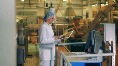 Bir kadın ile bir dizüstü bilgisayar bir gıda üretim fabrikasında çalışıyor..