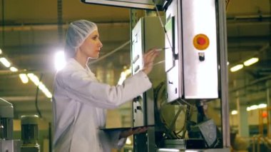 Fabrika ekipmanları, gıda üretim fabrikasında çalışan bir kadın denetler.