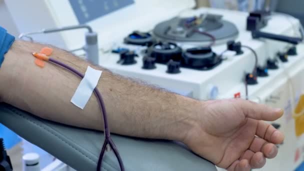 Ένας άνθρωπος δωρίζει αίμα σε μια κλινική, μετάγγιση μηχάνημα έργων. — Αρχείο Βίντεο