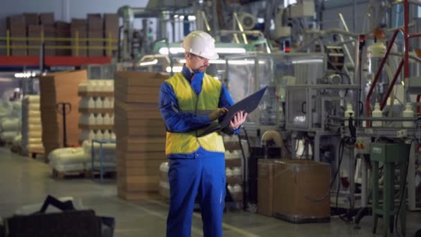 Funcionário da planta com um laptop está no meio de uma unidade produtora — Vídeo de Stock