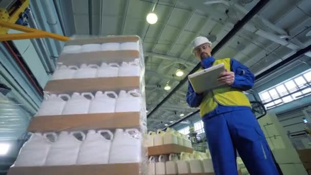 A supervisor is observing plastic containers getting wrapped into cellophane — Stock Video