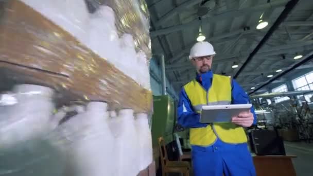 Рабочий-мужчина осматривает процесс упаковки пластиковых канистр — стоковое видео