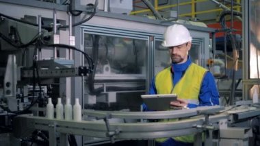 Plastik kaplar taşıma makineleri bir erkek işçi tarafından denetlenir