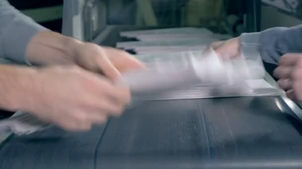 Люди берут бумагу с типографского конвейера, закрывают . — стоковое видео