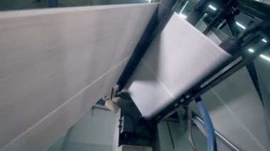 Çalışırken gazete sayfalarında yer özel bir konveyör, alttan görünüm.