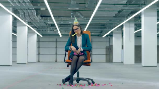 Empleado de oficina lanza confeti y sopla un silbato festivo, sentado en una silla . — Vídeo de stock