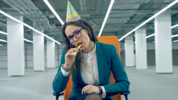 Triste mujer de negocios sonando un silbato festivo, usando una gorra de cumpleaños . — Vídeo de stock