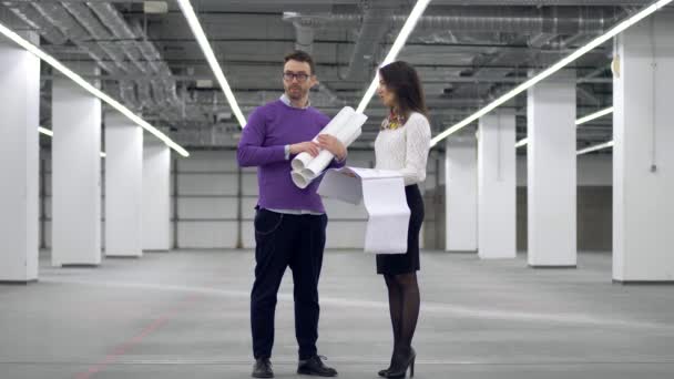 Två arkitekter titta på en plan, hålla den i händerna, och diskutera ett projekt. — Stockvideo