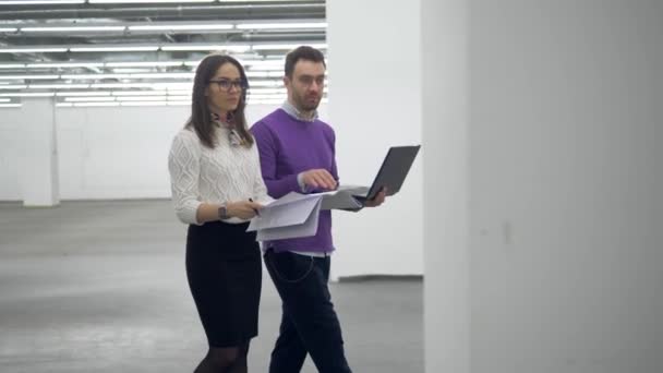 Engenheiros caminham em uma instalação, trabalhando com um laptop e documentos . — Vídeo de Stock