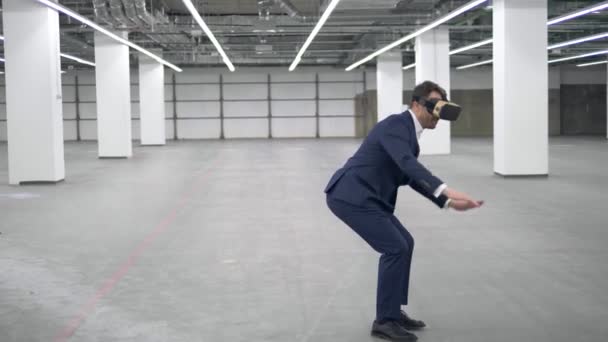 Un homme d'affaires saute en portant un casque VR dans un bureau . — Video