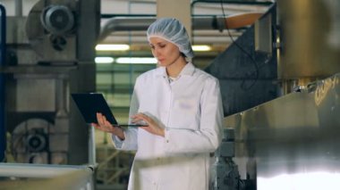 Kadın uzman fabrika tesis içinde bir laptop üzerinde çalışıyor