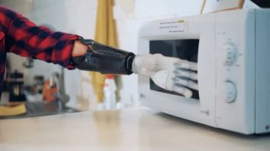 El protezi ile özürlü kadın bir mikrodalga ile çalışıyor, yakın çekim.