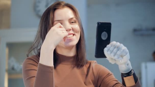 Een meisje met bionische prothese onderhandelingen over een telefoon, close-up. — Stockvideo