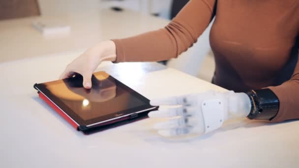 Gehandicapte persoon bezit een tablet met hand prothese, close-up. — Stockvideo