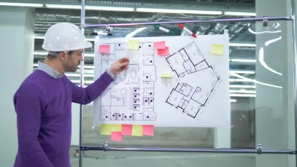 En ingenjör använder mätinstrument, arbetar med en plan på en bräda. — Stockvideo