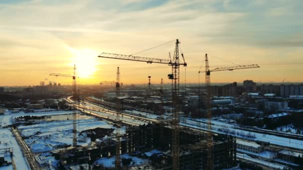 Paysage urbain enneigé avec grues dans le lot de construction — Video