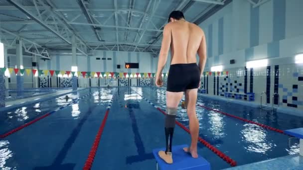 Handicapped swimmer warms up near a pool, leg prosthesis. — Stock Video