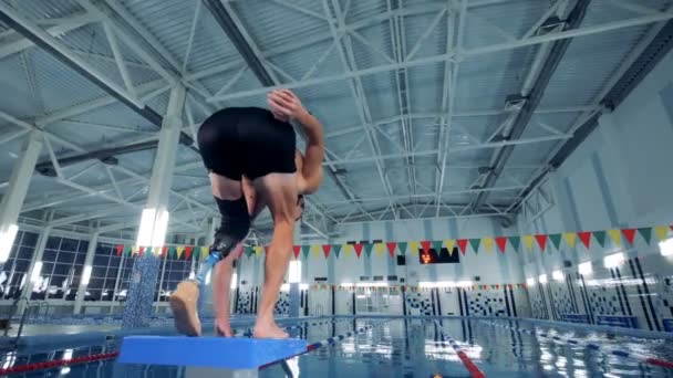 Un hombre con una prótesis salta a una piscina, pierna artificial . — Vídeo de stock