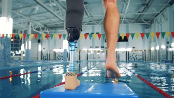 Simmare med en benet protes utbildning nära en pool, bionic utrustning. — Stockvideo