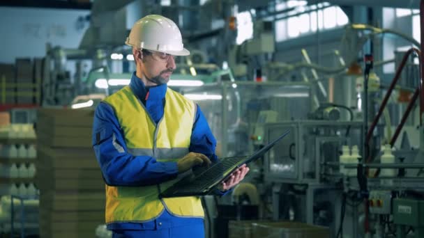 Un hombre en ropa de trabajo está inspeccionando el proceso de producción de plástico — Vídeos de Stock