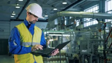 Bir dizüstü bilgisayar işletim erkek bir uzman ile Plastik Fabrikası