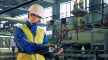 Erkek uzmanı plastik bir bitkinin bir tesiste bir dizüstü bilgisayar üzerinde çalışıyor