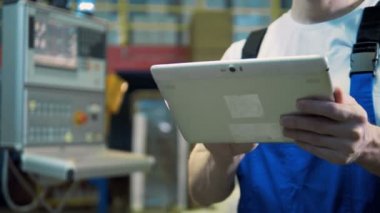 Bir erkek işçi fabrikada elinde tablet