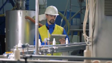 Plastik şişe konveyör erkek bir çalışanın kontrol altında gelen düşüyor